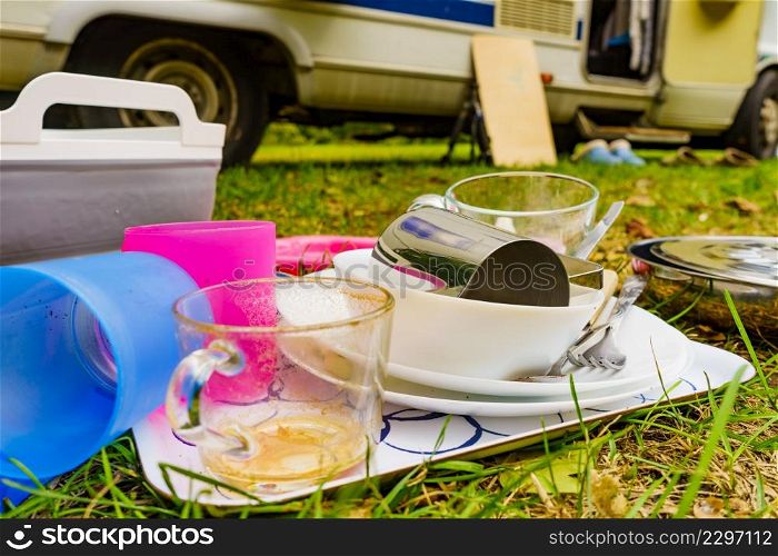 Dirty dishes outdoor against camper vehicle. Washing up on fresh air. Adventure, camping on nature, dishwashing outside.. Washing dishes, capming outdoor