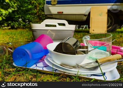 Dirty dishes outdoor against camper vehicle. Washing up on fresh air. Adventure, camping on nature, dishwashing outside.. Washing dishes, capming outdoor