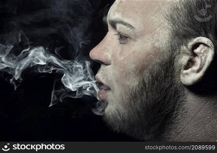 Dirty man smoking on a black background