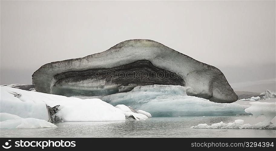 Dirty muddy melting iceberg floating in water