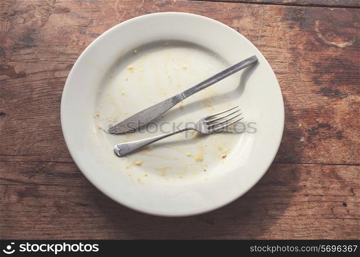 Dirty plate and cutlery on a wood table
