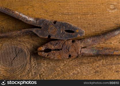 Dirty set of hand old rusty pliers tools on a wooden background. Equipment for locksmith and metalworking shop