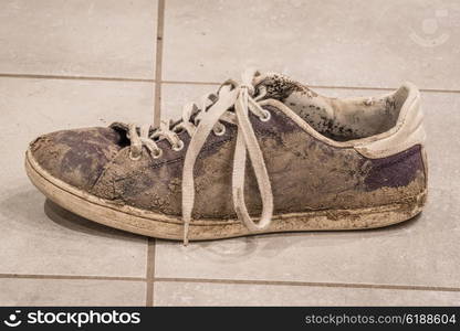 Dirty shoe with white laces covered with mud