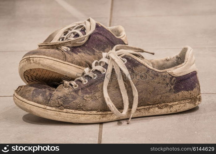 Dirty shoes with mud and soil on a floor