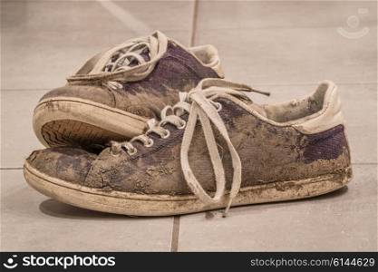 Dirty shoes with mud and soil on a floor