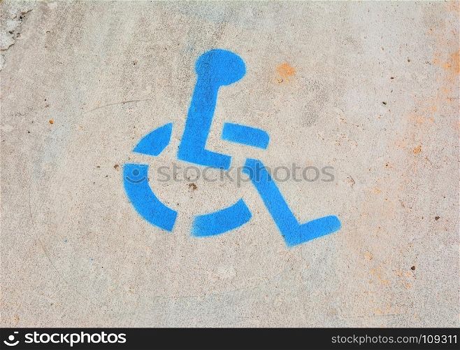 Disabled blue parking sign painted on asphalt.
