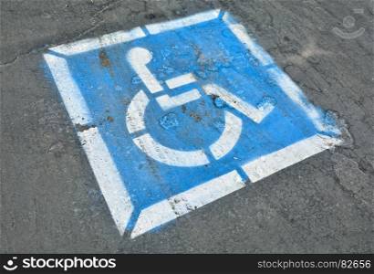 Disabled blue parking sign painted on dark asphalt.