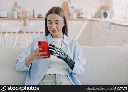 Disabled european woman is chatting on smartphone. Happy girl is holding the phone with bionic artificial arm. Attractive handicapped woman at home. Futuristic technology of artificial limbs.. Happy disabled european woman is chatting on smartphone. Equality and life quality concept.