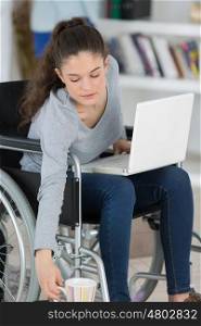 disabled female holding a cup while using her laptop