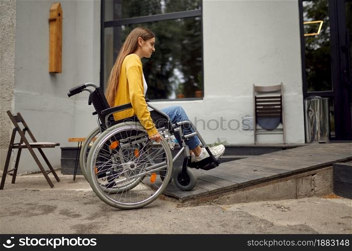 Disabled female student in wheelchair at the ramp in university cafe, disability. Handicapped young woman studying in college, paralyzed people get knowledge. Disabled student in wheelchair at the ramp in cafe