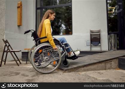 Disabled female student in wheelchair at the ramp in university cafe, disability. Handicapped young woman studying in college, paralyzed people get knowledge. Disabled student in wheelchair at the ramp in cafe