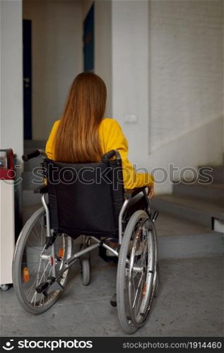 Disabled female student in wheelchair at the stairs, disability problems, university interior on background. Handicapped woman studying in college, paralyzed people get knowledge. Disabled female student in wheelchair at stairs