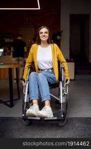 Disabled female student in wheelchair at the window, disability, bookshelf and university library interior on background. Handicapped young woman studying in college, paralyzed people get knowledge. Disabled female student in wheelchair at window