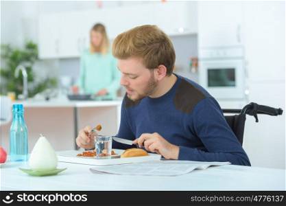 disabled man eating with wife in the background