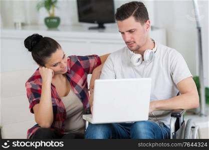 disabled man using laptop sitting next to his girlfriend