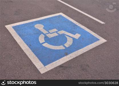 Disabled parking sign painted on asphalt.. Disabled blue parking sign painted on dark asphalt.