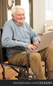 Disabled Senior Man Sitting In Wheelchair Using Laptop