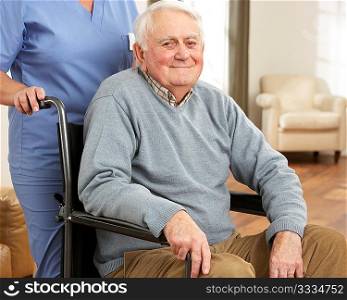 Disabled Senior Man Sitting In Wheelchair With Carer Behind
