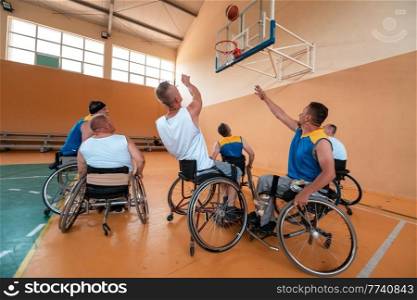 Disabled War or work veterans mixed race and age basketball teams in wheelchairs playing a training match in a sports gym hall. Handicapped people rehabilitation and inclusion concept.Hi quality photo. Disabled War veterans mixed race and age basketball teams in wheelchairs playing a training match in a sports gym hall. Handicapped people rehabilitation and inclusion concept