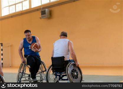 disabled war veterans in action while playing basketball on a basketball court with professional sports equipment for the disabled. High quality photo. disabled war veterans in action while playing basketball on a basketball court with professional sports equipment for the disabled