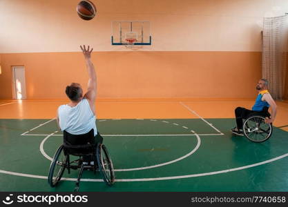 disabled war veterans in action while playing basketball on a basketball court with professional sports equipment for the disabled. High quality photo. Selective focus . disabled war veterans in action while playing basketball on a basketball court with professional sports equipment for the disabled