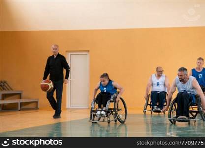 Disabled War veterans mixed race opposing basketball teams in wheelchairs photographed in action while playing an important match in a modern hall. High quality photo.. Disabled War veterans mixed race opposing basketball teams in wheelchairs photographed in action while playing an important match in a modern hall. 