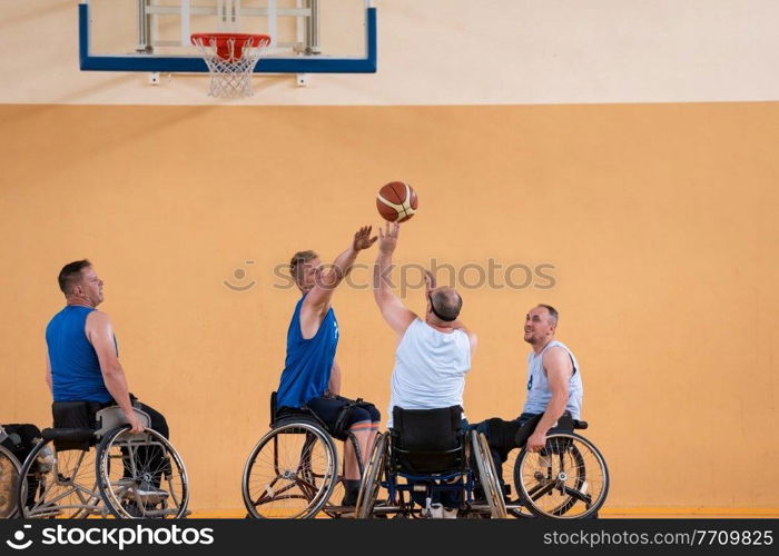 Disabled War veterans mixed race opposing basketball teams in wheelchairs photographed in action while playing an important match in a modern hall. High quality photo. Disabled War veterans mixed race opposing basketball teams in wheelchairs photographed in action while playing an important match in a modern hall. 