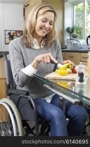Disabled Woman In Wheelchair Prepapring Meal In Kitchen