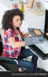 disabled woman in wheelchair putting bread in the oven