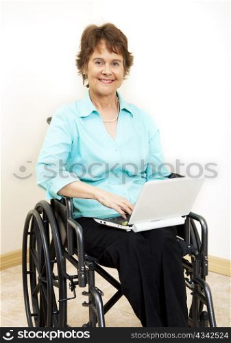 Disabled woman in wheelchair, typing on netbook computer.