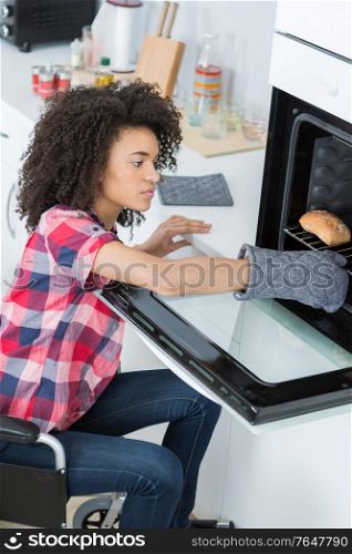 disabled woman in wheelchair using an oven