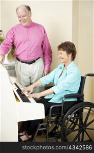 Disabled woman plays piano while an assistant turns pages for her.