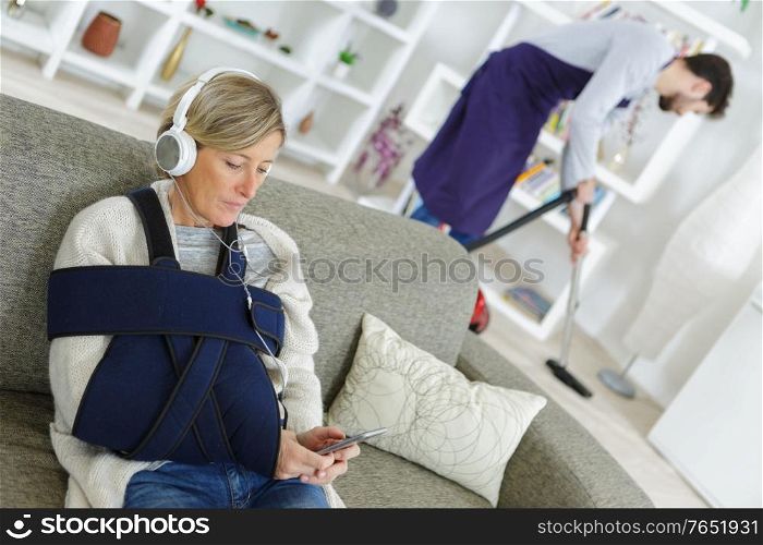 disabled woman using a cellphone while assistant cleaning