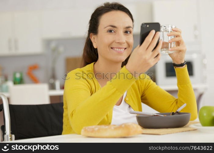 disabled woman using phone and holding a glass of water