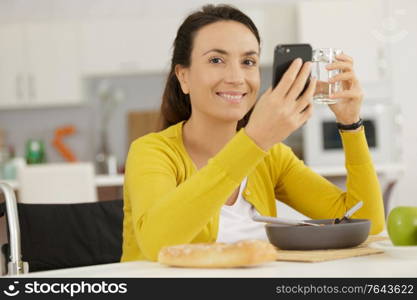 disabled woman using phone and holding a glass of water