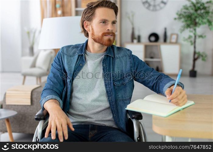 disabled young man at home writing on notebook