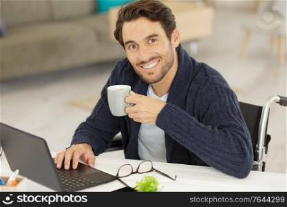 disabled young man using laptop and drinking coffee