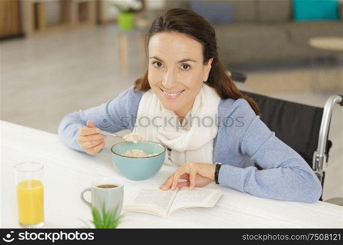 disabled young woman having breakfast and reading book