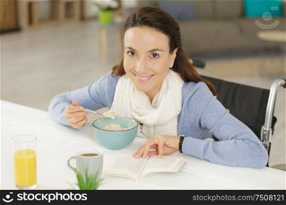 disabled young woman having breakfast and reading book