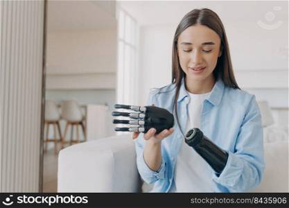 Disabled young woman is assembling bionic arm with hand. Prosthesis is connecting in wrist joint. Cyber sensor hand has processor chip and buttons. European girl has high tech carbon electronic hand.. Disabled young woman is assembling bionic arm with hand. Prosthesis is connecting in wrist joint.
