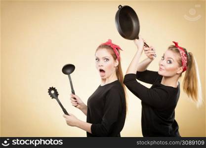 Disagreement in cooking. Kitchen accessories equipment in move. Girls having argument fight. Expression of fear and anger.. Kitchen fight between retro girls.