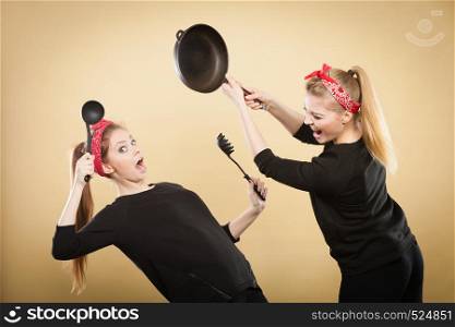 Disagreement in cooking. Kitchen accessories equipment in move. Girls having argument fight. Expression of fear and anger.. Kitchen fight between retro girls.