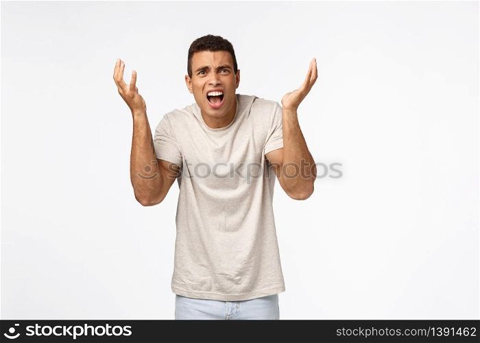 Disappointed and freak-out, bothered handsome man in t-shirt, raising hands up frustrated and displeased, arguing, complaining over unfair failure, losing competition, standing upset white background.. Disappointed and freak-out, bothered handsome man in t-shirt, raising hands up frustrated and displeased, arguing, complaining over unfair failure, losing competition, standing upset white background