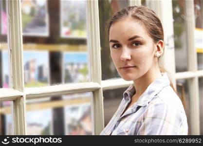 Disappointed Young Woman Looking In Window Of Estate Agents
