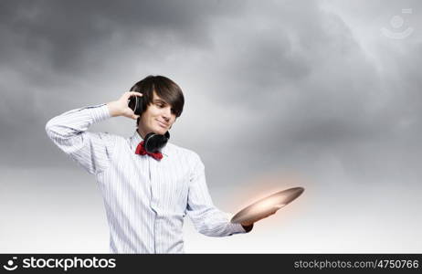 Disco dj. Young man dj wearing headphones and holding plate