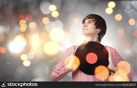 Disco party. Young handsome man with disco plate in hands