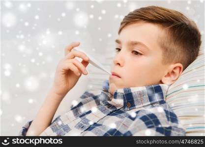 disease, healthcare and medicine concept - ill boy with flu measuring temperature by thermometer at home over snow