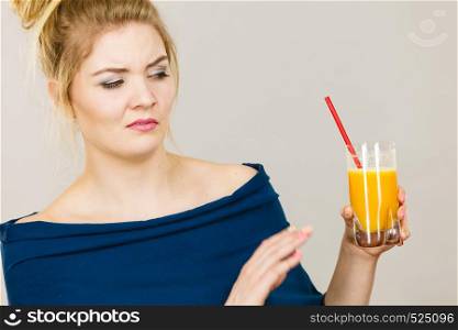 Disgusted blonde woman holding orange juice, lady not enjoying fresh fruit drink.. Disgusted woman holding orange juice