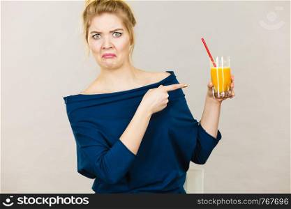 Disgusted blonde woman holding orange juice, lady not enjoying fresh fruit drink.. Disgusted woman holding orange juice