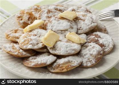 Dish Dutch mini pancakes called poffertjes with white sugar and butter